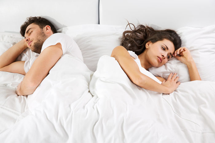 Upset couple lying side by side in bed