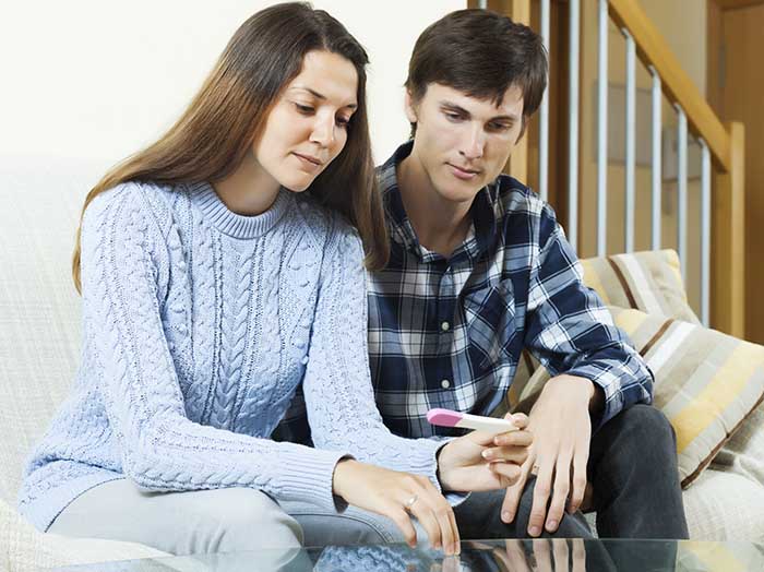 worried couple with pregnancy test at table in home interior